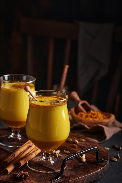 Kurkuma gouden melk latte met kaneelstokjes en honing. Gezonde ayurvedische drank. Trendy Aziatische natuurlijke detoxdrank met kruiden voor veganisten. Ruimte kopiëren.