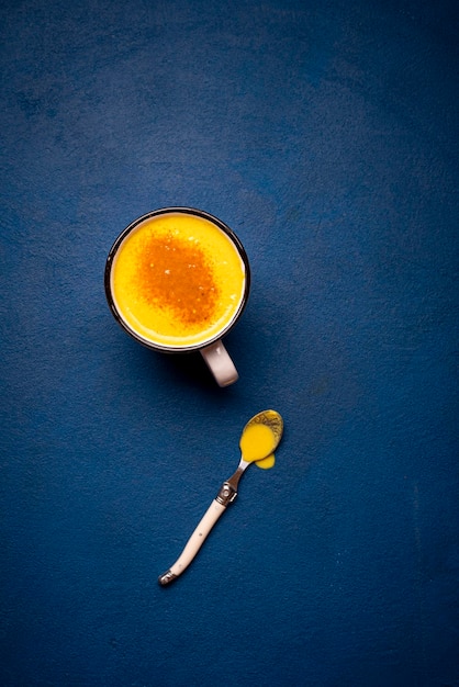 Kurkuma latte op een blauwe tafel Gezonde drank Gele melkbeker