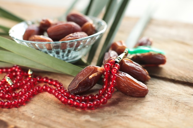 Kurma or dried dates, rosary on wooden background.