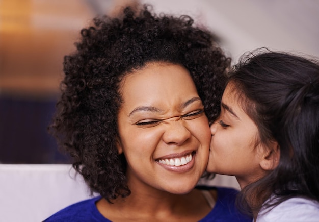 Kus moeder en meisje met liefde, hechting en quality time met geluk thuis en liefhebbende familie ouder of mama met dochter vrouwelijk kind en kind kussende moeder vrolijk en zorgzaam in de woonkamer