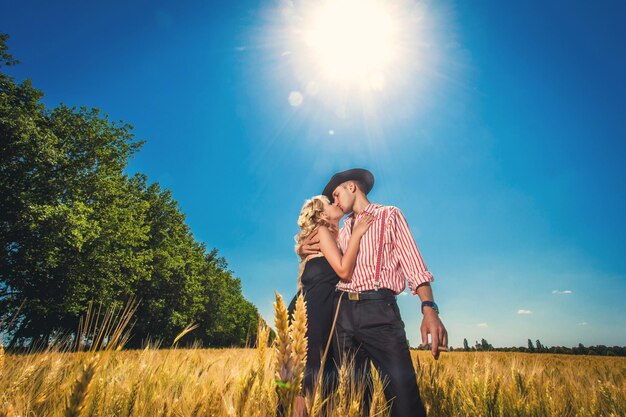 Kussende man en vrouw staan op een tarweveld