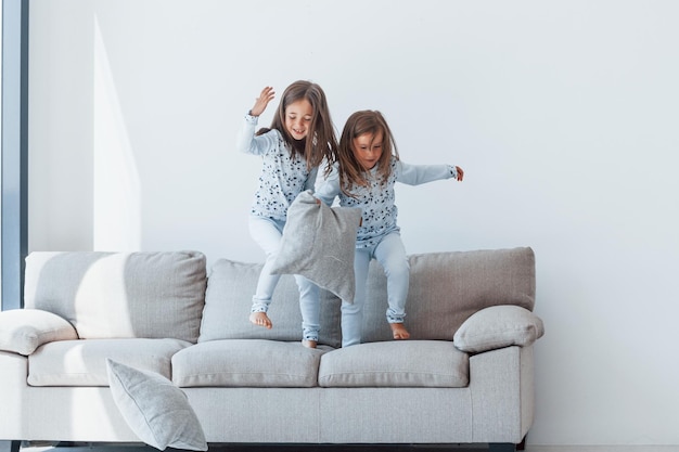 Kussengevecht Twee schattige kleine meisjes binnenshuis samen thuis Kinderen hebben plezier