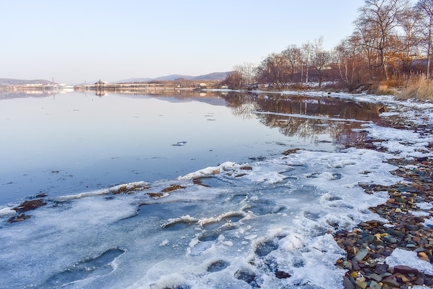 Kust bedekt met smeltende sneeuw en een spiegelend wateroppervlak