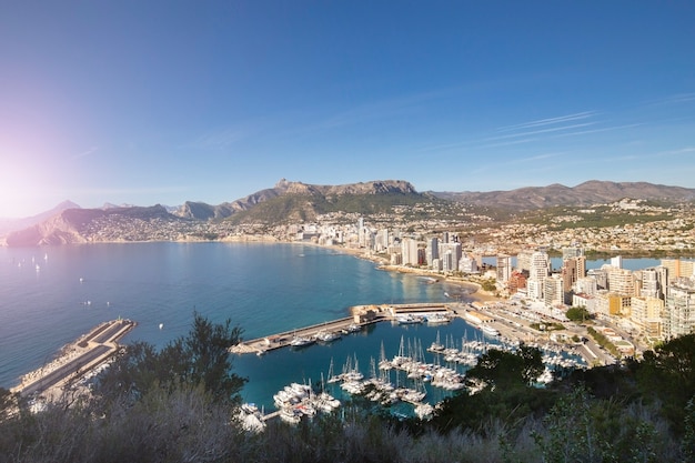 Kustlijn van de mediterrane badplaats calpe spanje met zee en jachten meer wolkenkrabbers en bergen...