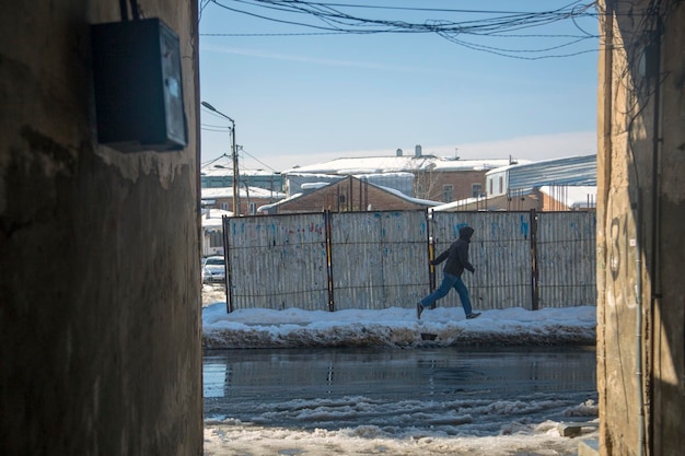 Kutaisi Georgia 3 feb 2020 Een man rent door een vuile besneeuwde stadsstraat