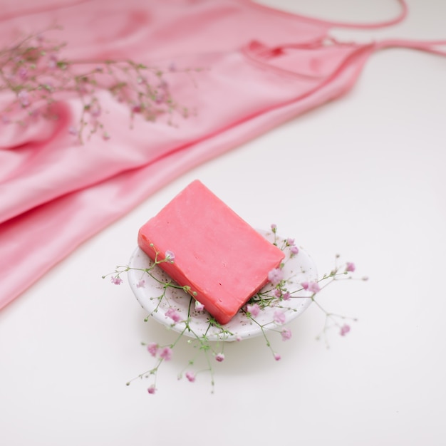 Kuuroordsamenstelling met roze zeepstaaf met ceramische de zijdestof van de zeepbak en bloemen