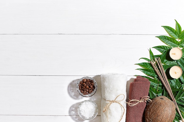 Kuuroordstilleven met handdoekkaarsen en groene bladeren op een wit houten oppervlak