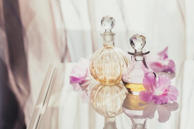 Kuuroordstilleven met parfum- en aromatische olieflessen omgeven door bloemen, op een lichte ondergrond