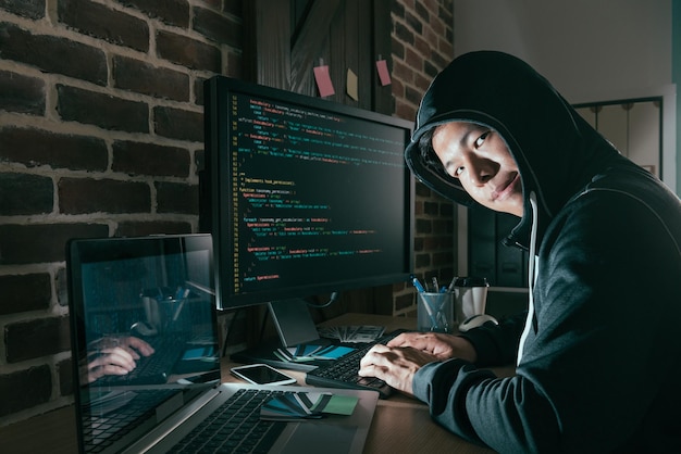 Foto kwaadaardige jonge computerprogrammeur als hacker en ontwerp een slecht gegevenssysteem dat informatie van het wereldwijde bedrijfsbedrijf hackt om losgeld op te lichten.