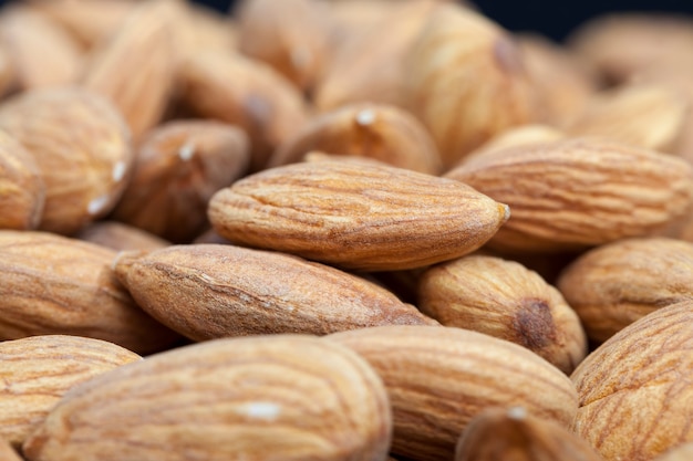 Kwaliteit rauwe noten klaar om te eten, amandelen op de keukentafel tijdens het koken, amandelen vers en geschild, het oppervlak van de noten is niet perfect en heeft enkele natuurlijke gebreken door hun bereiding in voedsel