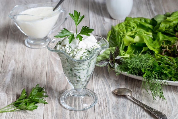 Foto kwark met groenen en yoghurt op een lichte houten achtergrond.