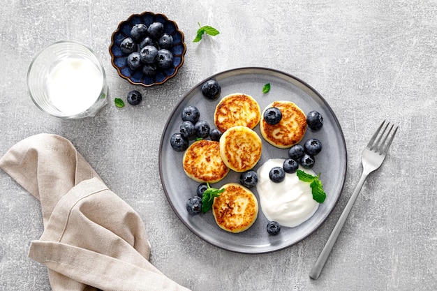 Kwarkbeignets met verse bosbessen en yoghurt voor het ontbijt, kopieer de ruimte van bovenaf