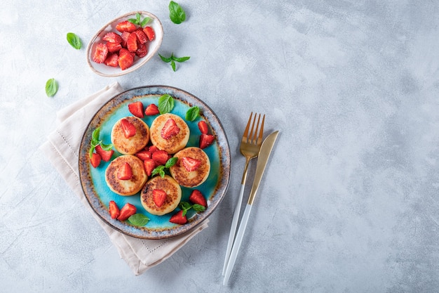 Kwarkpannenkoekjes met aardbeien en munt op een blauwe plaat bovenaanzicht foto met vrije ruimte