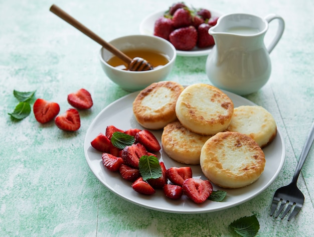 Kwarkpannenkoekjes, ricottabeignets op keramische plaat met verse aardbeien. Gezond en heerlijk ochtendontbijt.