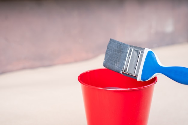 kwast en emmer met verf naast een buitenmuur van een gebouw