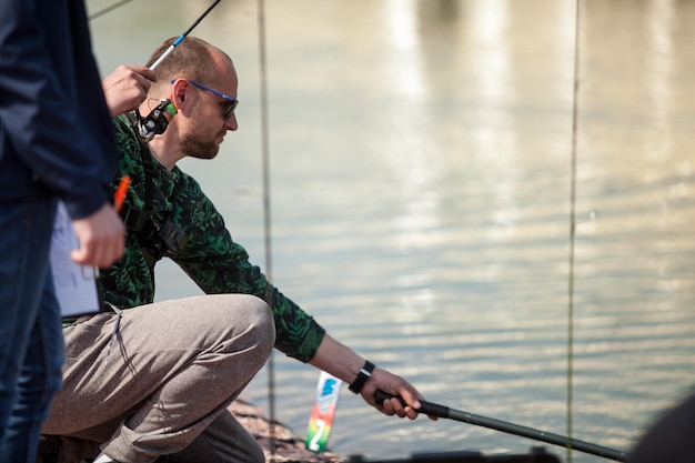 Kyiv, Ukraine April 16, 2018. A caucasian fisherman catches fish with a landing net on the lake.