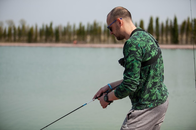 Kyiv, Ukraine April 16, 2018. Caucasian fisherman catches fish with a spinning rod on the lake.