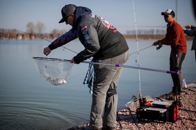 Kyiv, Ukraine April 16, 2018. A fisherman cuts off a fishing line for a fish in a landing net.