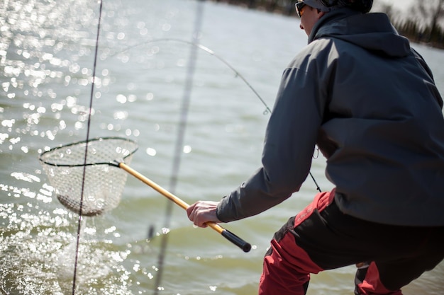 Kyiv, ukraine april 16, 2018. a fisherman with a spinning rod, holds a fish in a landing net