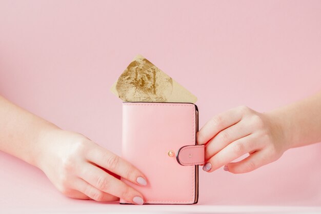 Photo kyiv, ukraine - february 22, 2019: wallet and credit card in woman's hand on pink background