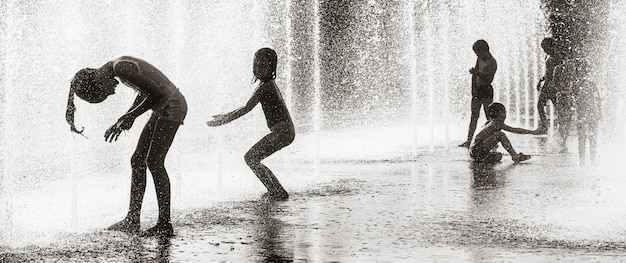 КИЕВ, УКРАИНА - 29 июля 2020 г .: Дети играют в фонтане и наслаждаются прохладными струями воды в жаркий день. Жаркое лето. Фонтаны возле фабрики Roshen в Киеве