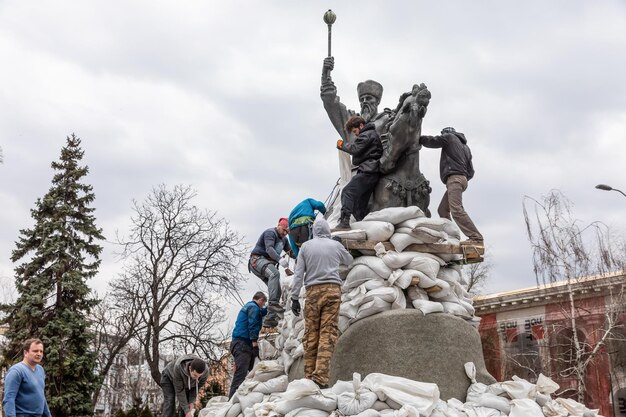 KYIV UKRAINE Mar 26 2022 Monument to Hetman Sahaidachny with sandbags to protect against Russian shelling in Kyiv A group of young people cover the monument with sandbags