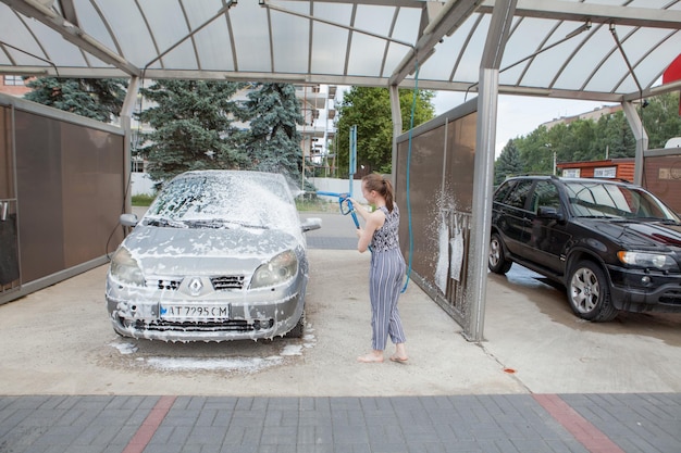 Киев Украина 15 мая 2019 года Молодая женщина с ведром и тряпкой моет красную машину