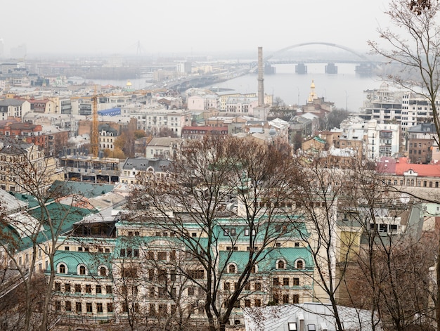 Kyiv, Ukraine - Nov. 16, 2019: Cityscape of Podol district in Kyiv city at foggy day. Kontraktova square and Ferris wheel