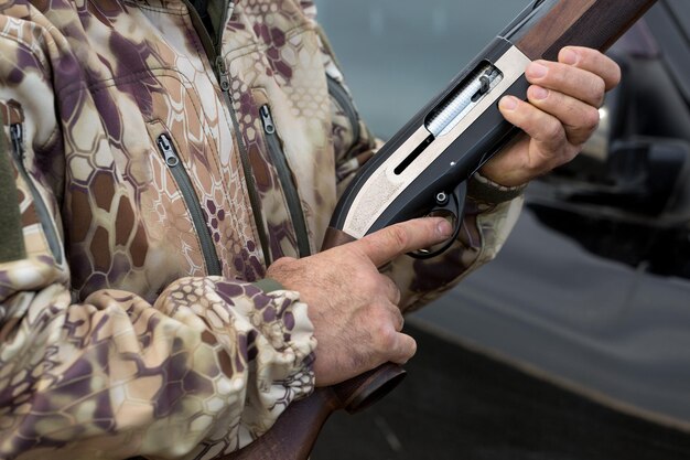Laadt een jachtgeweer met gladde loop op jacht op een fazant met honden Een jager in camouflage staat met een wapen