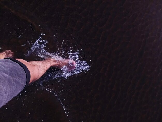 Foto laag gedeelte van de man die water spat op het strand