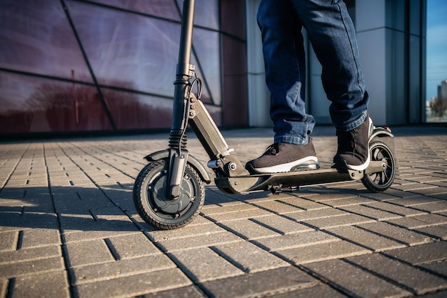 Laag gedeelte van de man met stootscooter op het voetpad