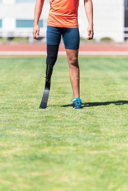 Foto laag gedeelte van een atleet met een prosthetisch been die op het veld staat
