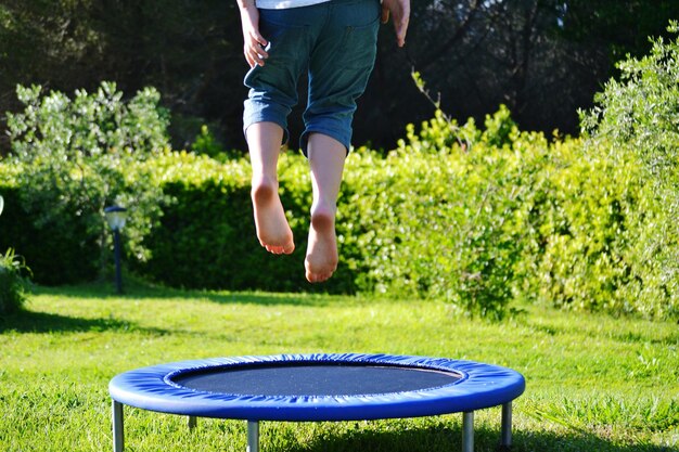 Foto laag gedeelte van een jongen die op een trampoline springt in het park