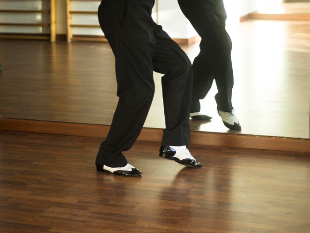 Foto laag gedeelte van een man die op de hardhouten vloer in de studio danst