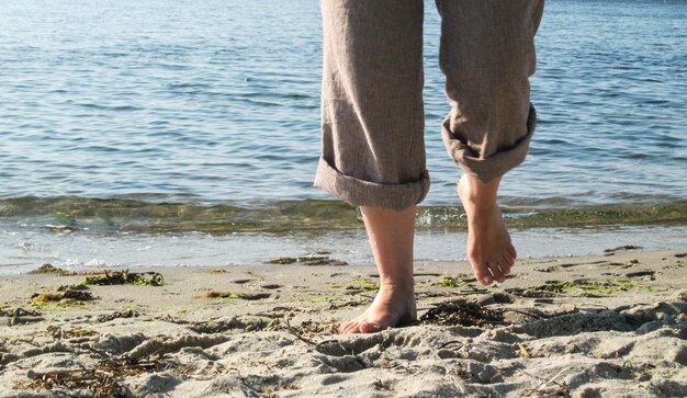 Foto laag gedeelte van een man die op een zonnige dag op het strand loopt