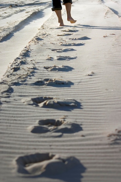 Laag gedeelte van een man die op het strand in het zand loopt