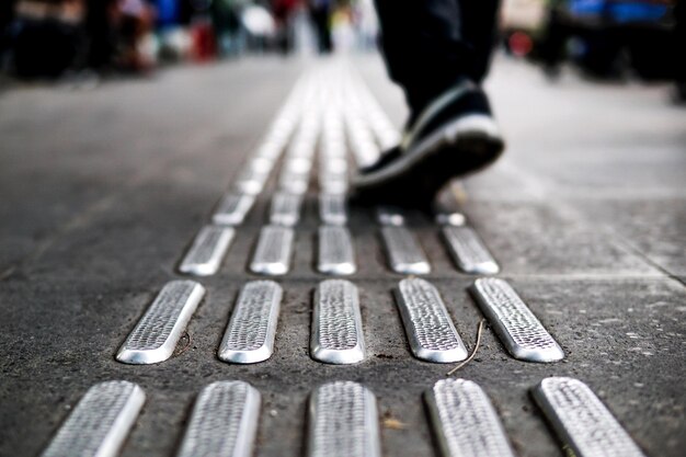 Foto laag gedeelte van een man die op tactile asfalt in de stad loopt