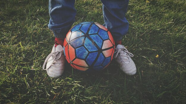 Foto laag gedeelte van een man met een voetbal op een grasveld