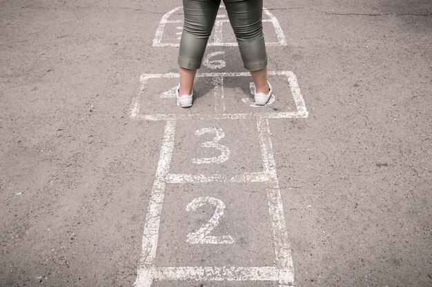 Foto laag gedeelte van een meisje dat hopscotch speelt op de weg