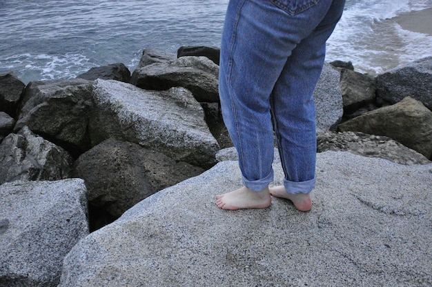 Foto laag gedeelte van een vrouw die op een rots bij de zee staat