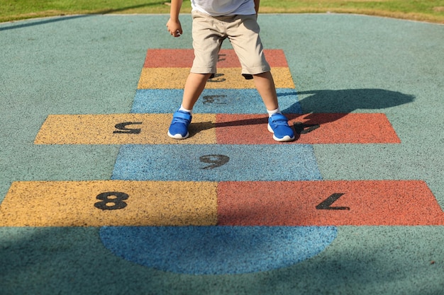 Foto laag gedeelte van jongen die hopscotch speelt op de speeltuin