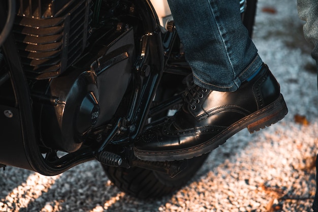 Foto laag gedeelte van man die schoenen draagt en buiten op een motorfiets staat