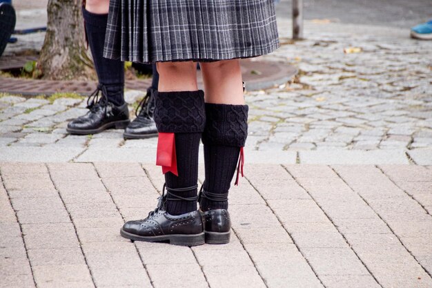 Foto laag gedeelte van meisje en jongen die kilt dragen terwijl ze op straat staan