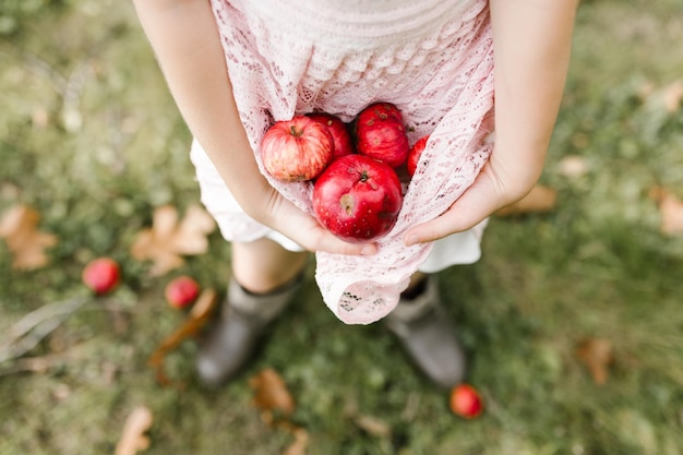 Laag gedeelte van meisje met appels terwijl ze op het veld staat