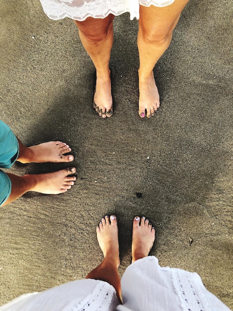 Foto laag gedeelte van vrienden staan op het zand op het strand