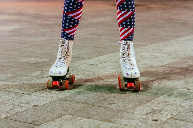 Laag gedeelte van vrouw die legging met amerikaanse vlag draagt terwijl ze op rolschaats op voetpad