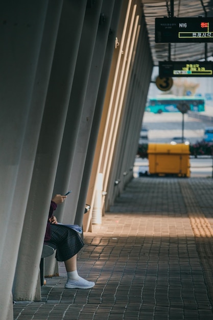 Laag gedeelte van vrouw die telefoon gebruikt terwijl ze op het treinstation zit