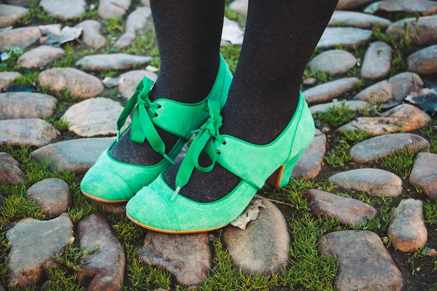 Foto laag gedeelte van vrouw met groene schoenen die op rots staat