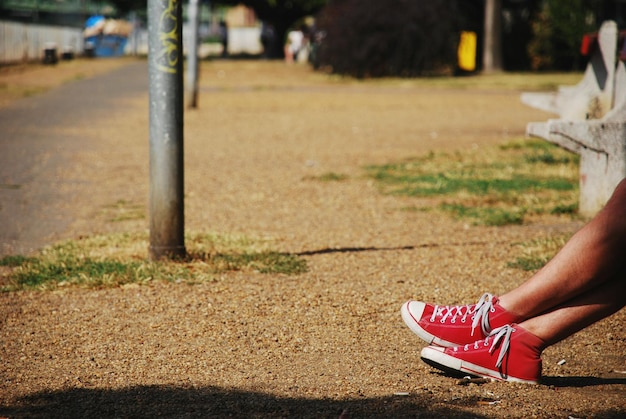 Foto laag gedeelte van vrouw met rode schoenen die aan de kant van de weg rust