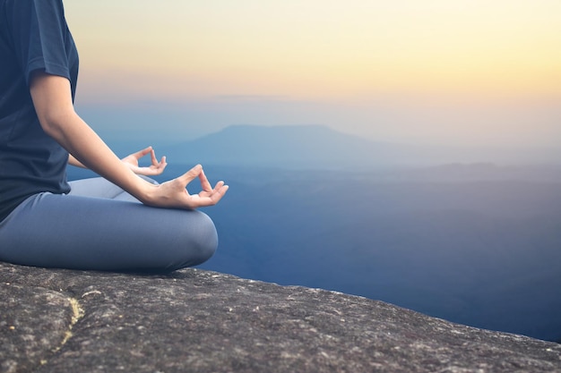 Laag gedeelte van vrouwelijke meditatie op de berg tijdens zonsondergang